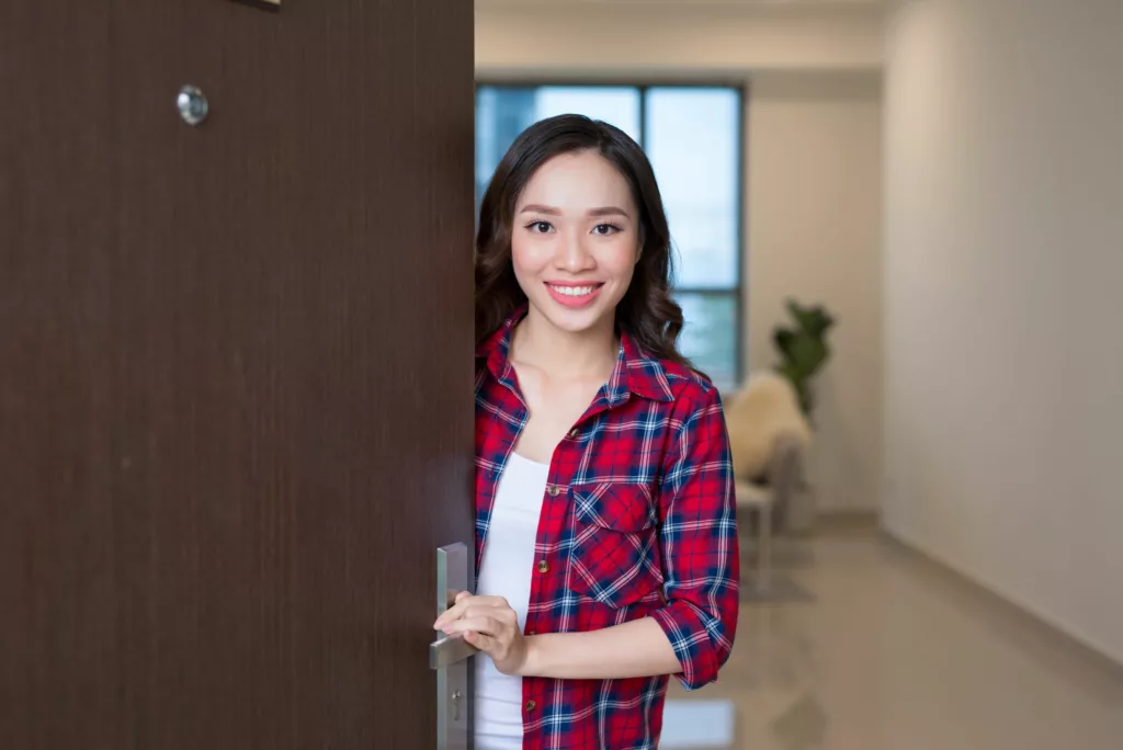 cheerful asian awoman inviting people enter home